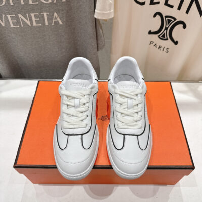 此款 Hermès 高仿莆田鞋白色黑邊低筒運動鞋以品牌經典運動鞋輪廓為基礎，透過黑色描邊線條勾勒鞋面結構，使整體視覺更具層次且不顯繁複。鞋面選用高品質皮革材質製作，表面細緻平滑，縫線排列工整，線條比例依原版鞋型調整，呈現自然俐落的外觀。內裡包覆柔軟，鞋舌與後跟貼合度佳，搭配回彈適中的鞋墊設計，長時間行走依然保持良好舒適度。外底採耐磨橡膠材質，抓地力穩定，日常外出、通勤或休閒活動皆相當合適。配色乾淨百搭，黑邊細節提升整體辨識度，無論搭配牛仔褲、休閒褲或簡約穿搭都能輕鬆駕馭，是高仿莆田鞋推薦中兼顧外觀完成度、腳感與耐用度的熱門選擇。